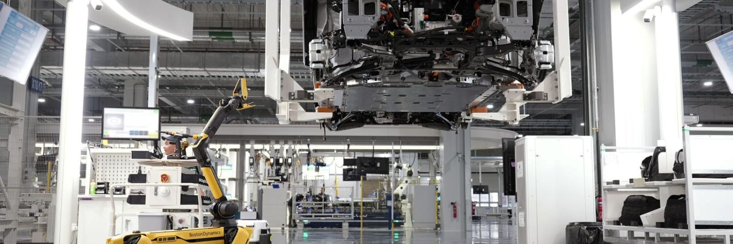 Yarı zamanda iki kat iş yazısı için görsel: aydınlık bir fabrika zemininde yürüyen dört bacaklı sarı robot