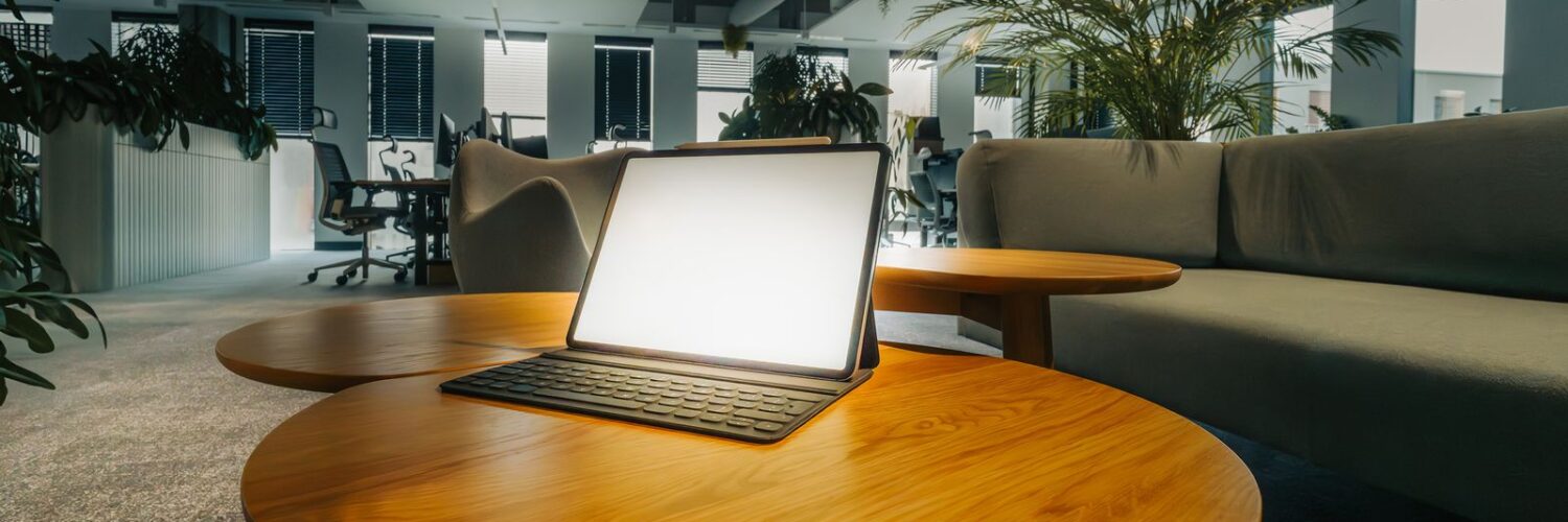 Ahşap masada açık duran bir dizüstü bilgisayarla boş bir ofis salonu