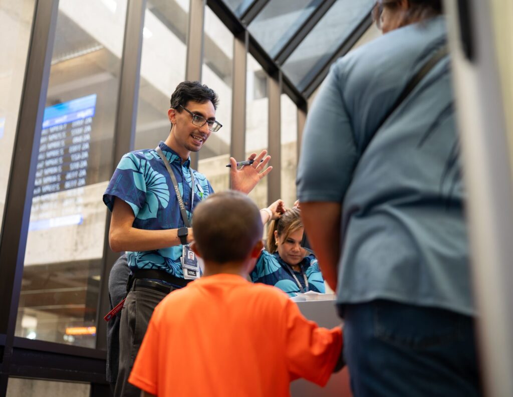 Honolulu Havalimanı'ndaki engelli prova uçuşunda bir çocuk Hawaiian Airlines check-in bankosunda görevlilerle birlikte