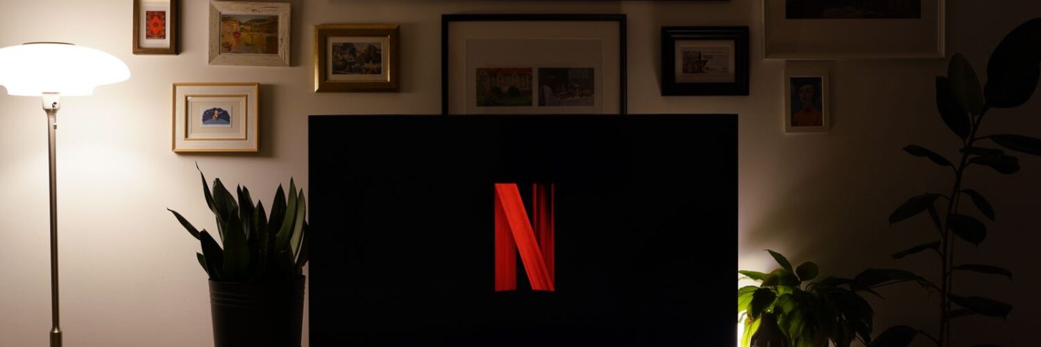 Karanlık bir oturma odasında ekranında Netflix logosu görünen televizyon