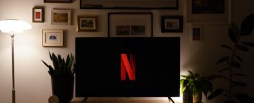 Karanlık bir oturma odasında ekranında Netflix logosu görünen televizyon
