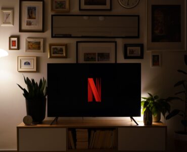 Karanlık bir oturma odasında ekranında Netflix logosu görünen televizyon