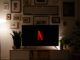 Karanlık bir oturma odasında ekranında Netflix logosu görünen televizyon
