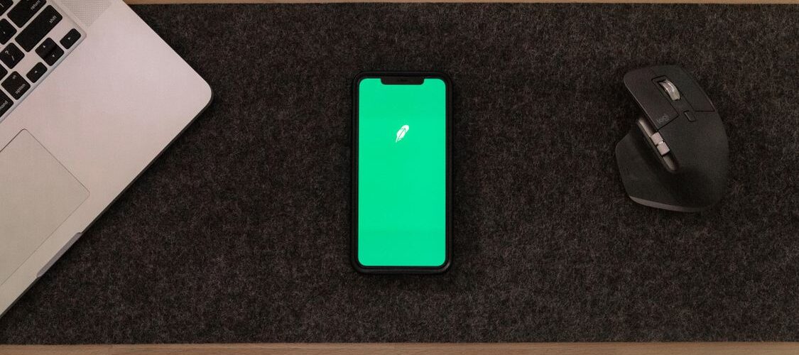 Ahşap masada dizüstü bilgisayar, akıllı telefon ve fare; yapay zekâ abonelik ve dijital araçlar teması